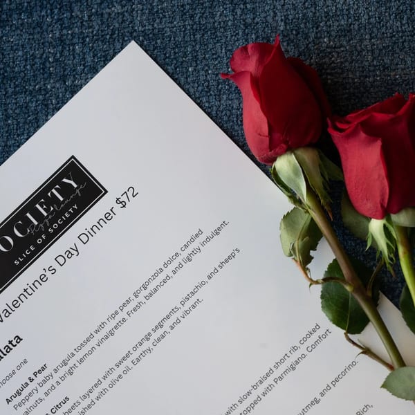 A Valentine's Day Dinner menu from Society Pizza Lounge, with two red roses on a blue textured surface.