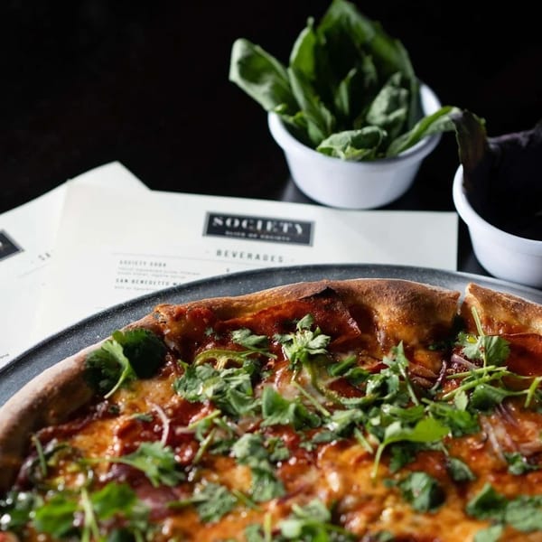 A Society restaurant menu and a pizza topped with cilantro, red onions, and jalapeños.