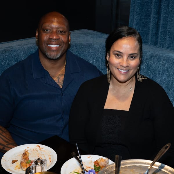 Smiling couple seated at a restaurant table with partially eaten pizza and drinks.
