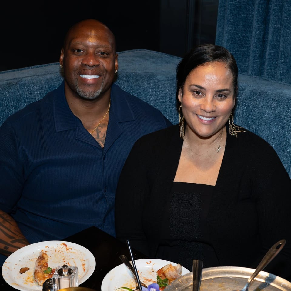 Smiling couple seated at a restaurant table with partially eaten pizza and drinks.