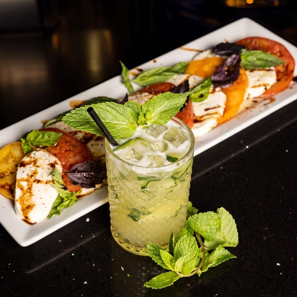 Caprese salad with red and yellow tomatoes, mozzarella, basil, and a cucumber mint cocktail.
